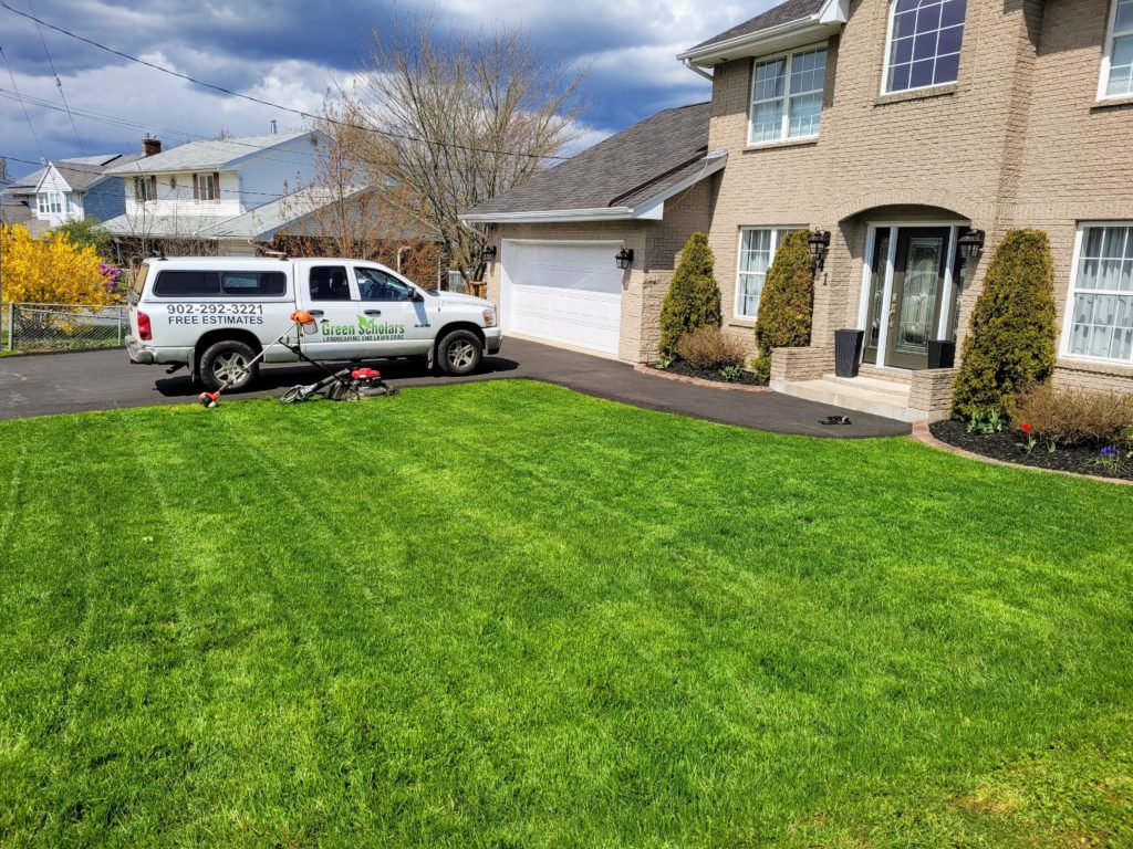front yard grass with a Green Scholars truck in the driveway