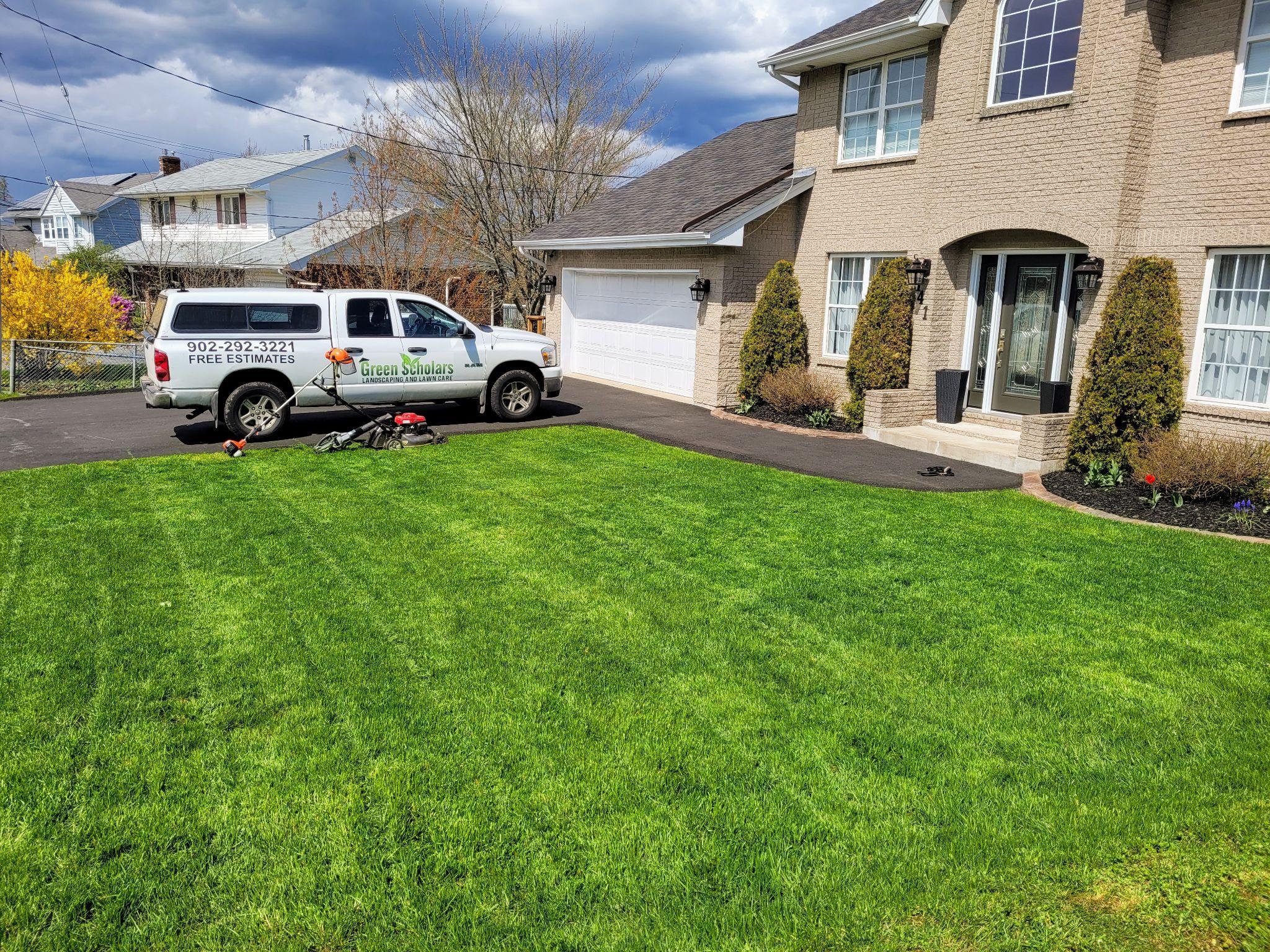 Green Scholars Landscaping truck parked near a freshly cut residential lawn.