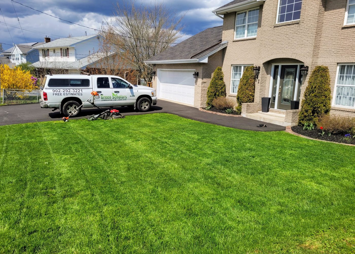 front yard grass with a Green Scholars truck in the driveway